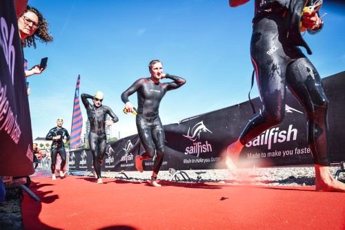 Triathleten im Neoprenanzug laufen aus dem Wasser